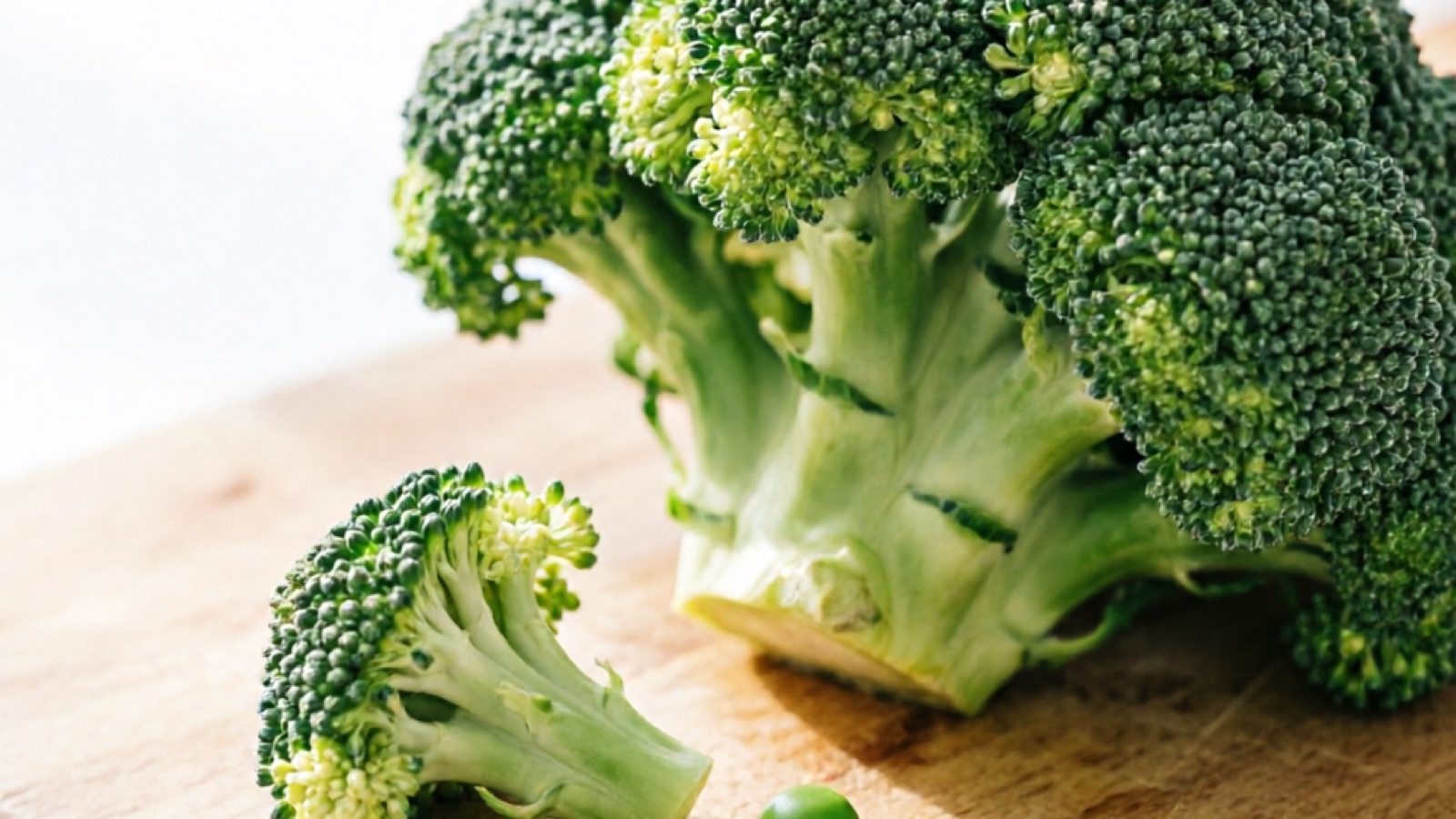 Close-up of raw broccoli florets on a cutting board, with a small piece cut for hamster portion size