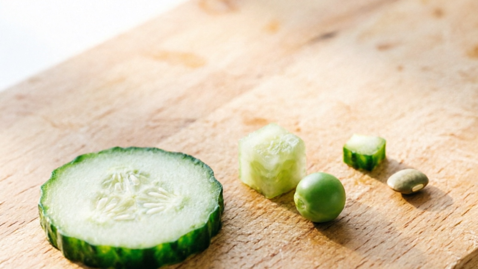 Cucumber portion sizes for different hamster breeds Cucumber slices of different sizes arranged for hamster portion comparison, with a pea for scale