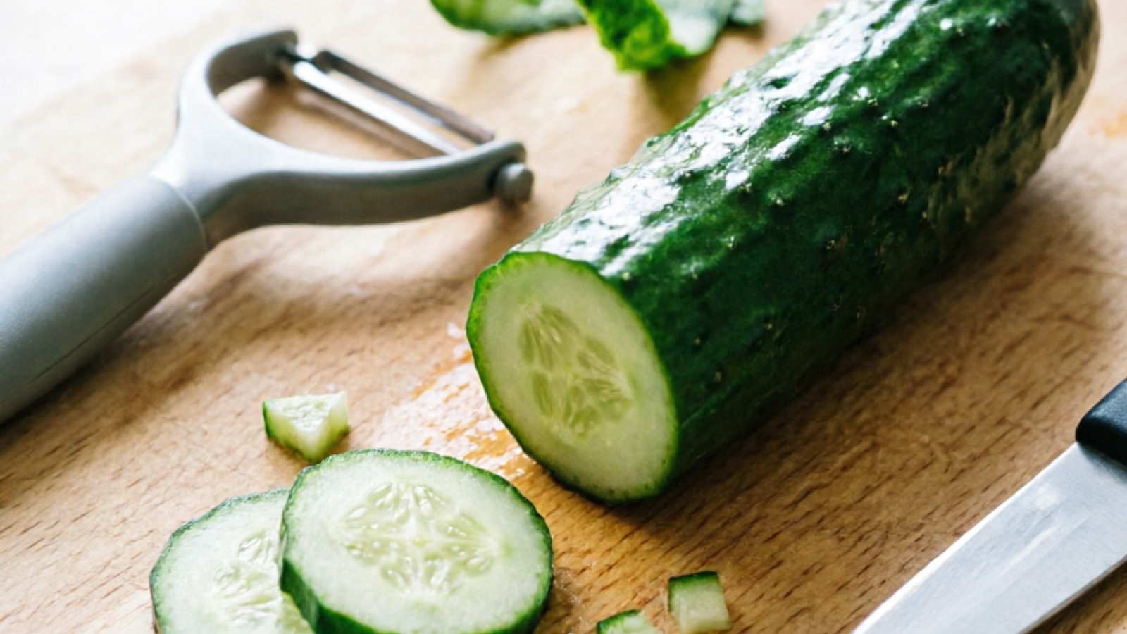 Preparing cucumber for hamster - washing, peeling, and cutting Washed cucumber being peeled and cut into hamster-sized pieces on a cutting board