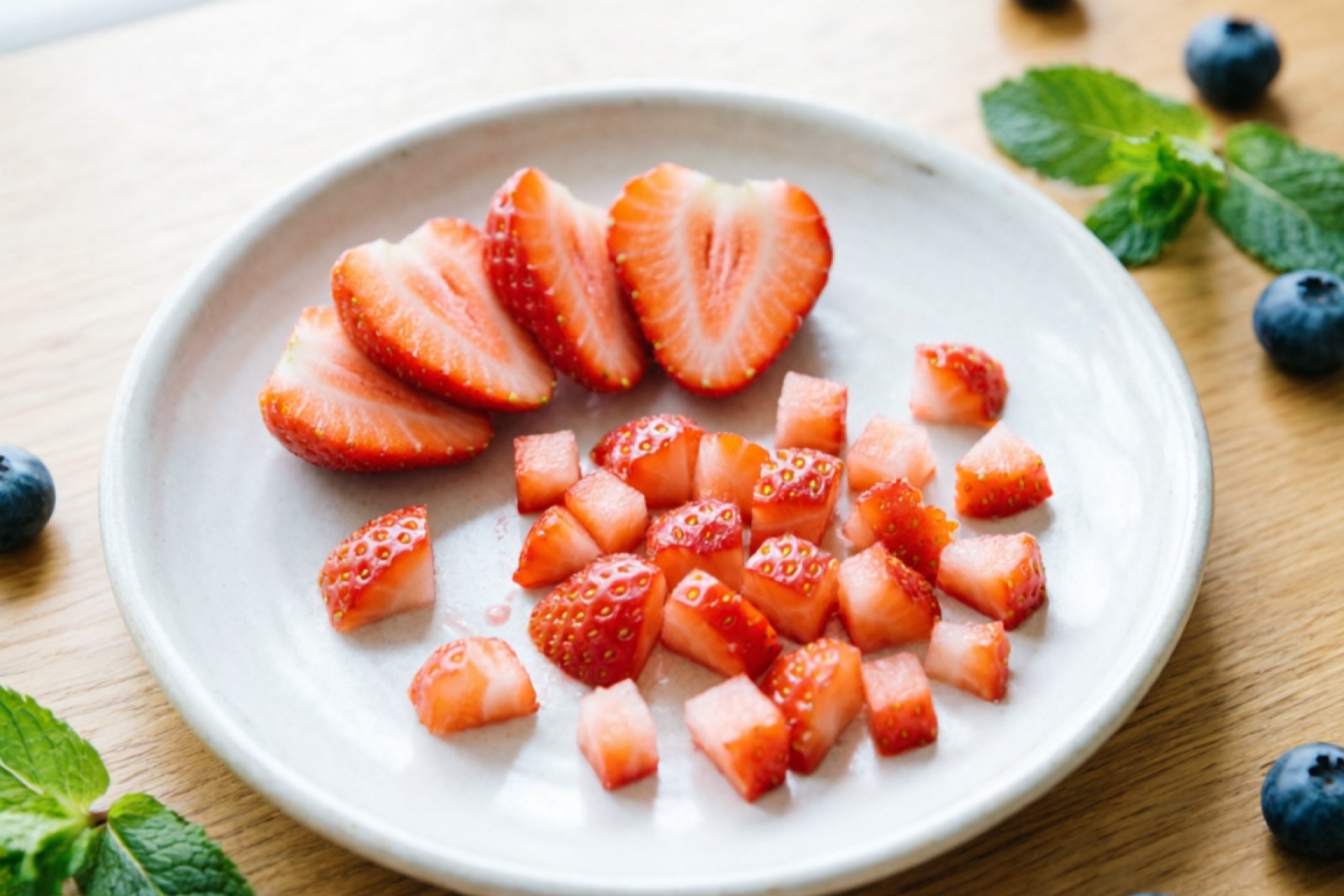 Fresh strawberry pieces cut into hamster-sized bites on a small plate